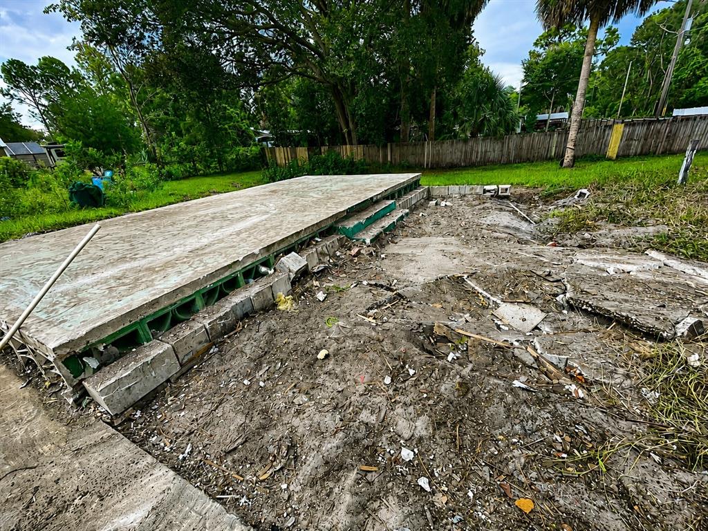 An elevated concrete foundation with steps sits on a dirt lot near a wooden fence — 27729 LUELLA AVENUE, PAISLEY, FL
