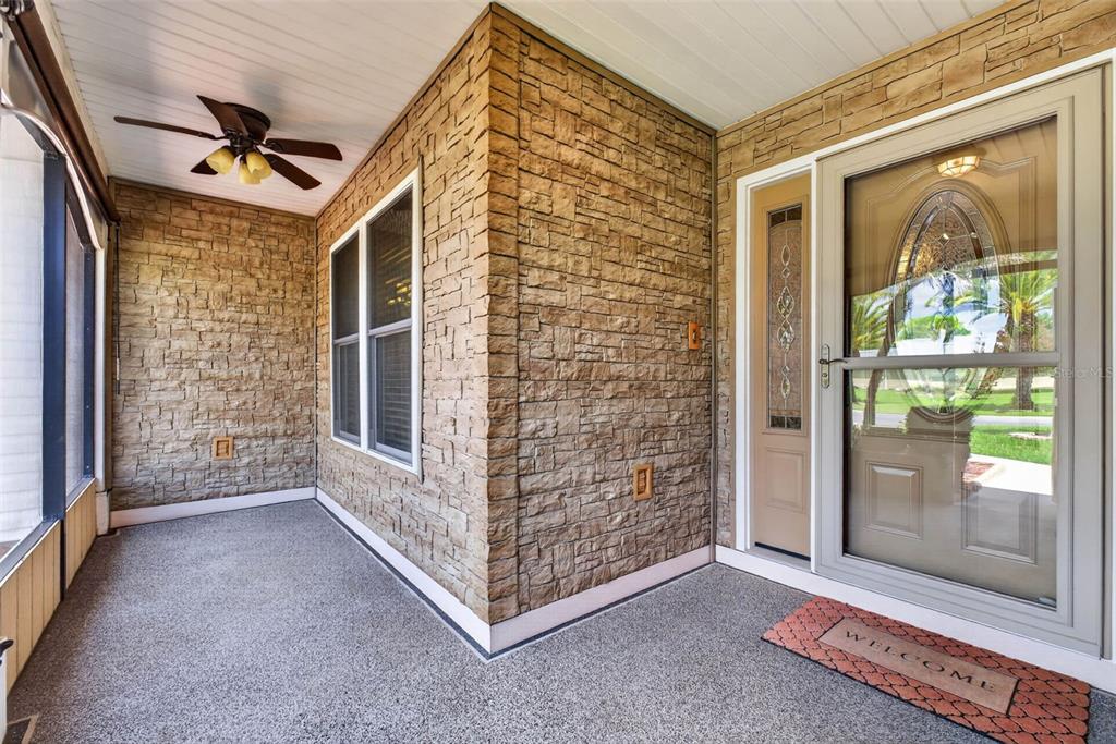 A covered porch features stone veneer walls, a ceiling fan, and a glass-paneled front door — 6031 SANDERLING DRIVE, LAKELAND, FL