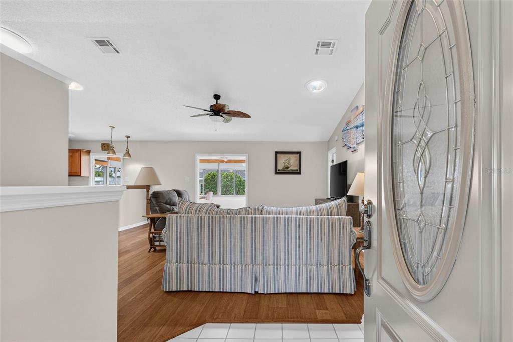 A view from an entryway into a living room with wood flooring and a sofa — 6031 SANDERLING DRIVE, LAKELAND, FL