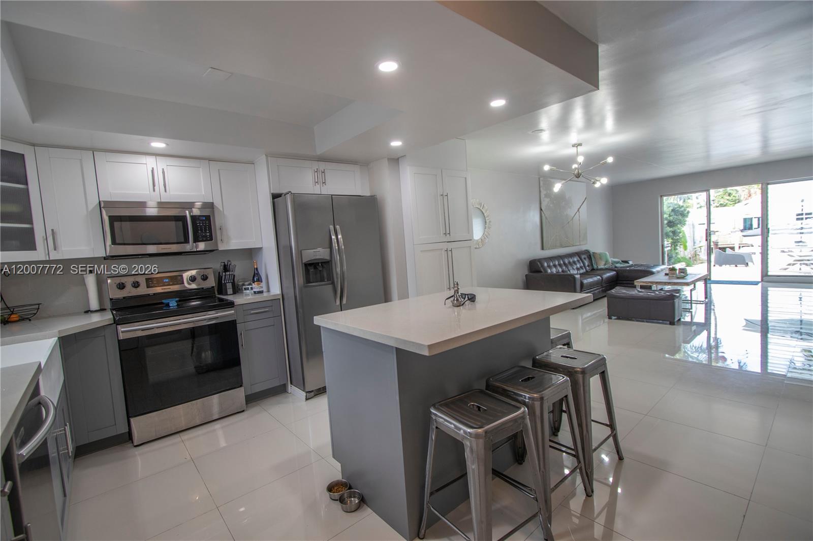 A modern kitchen with gray and white cabinetry, a central island, and stainless steel appliances — 2117 NE 123rd St, North Miami FL 33181, NORTH MIAMI, FL