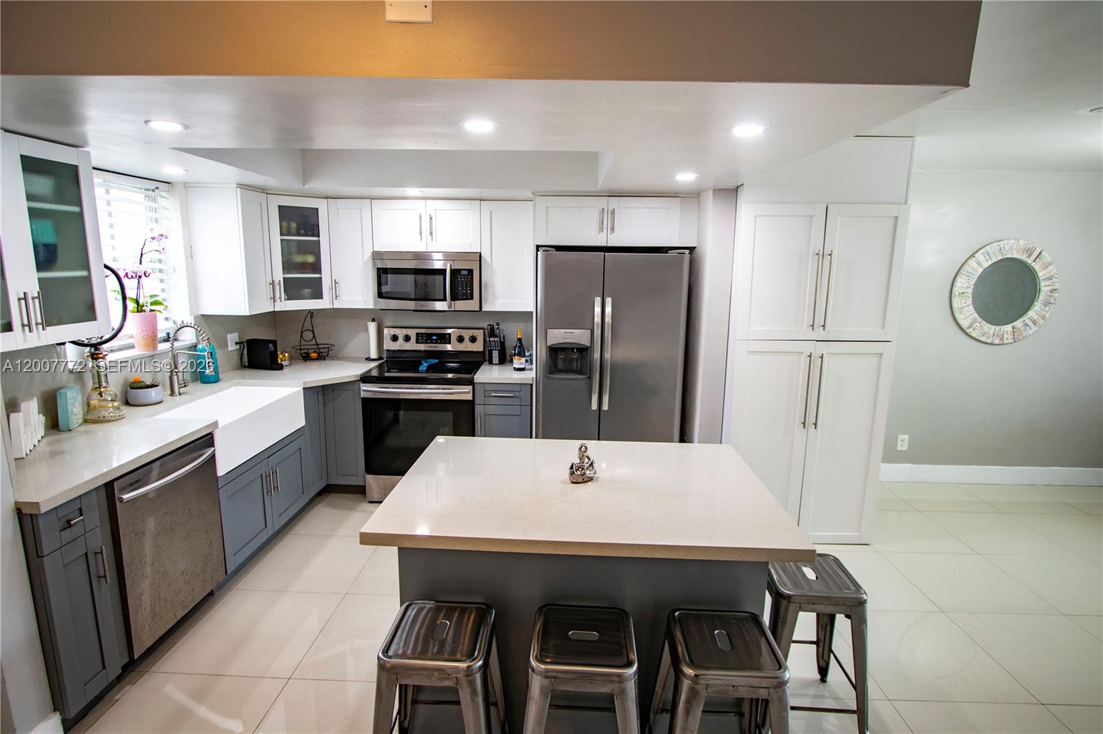 A modern kitchen features two-toned gray and white cabinetry, stainless steel appliances, and an island — 2117 NE 123rd St, North Miami FL 33181, NORTH MIAMI, FL