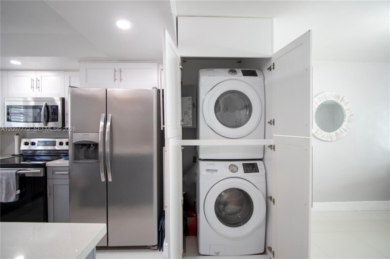 A kitchen features stainless steel appliances and a stacked washer and dryer in a cabinet — 2117 NE 123rd St, North Miami FL 33181, NORTH MIAMI, FL