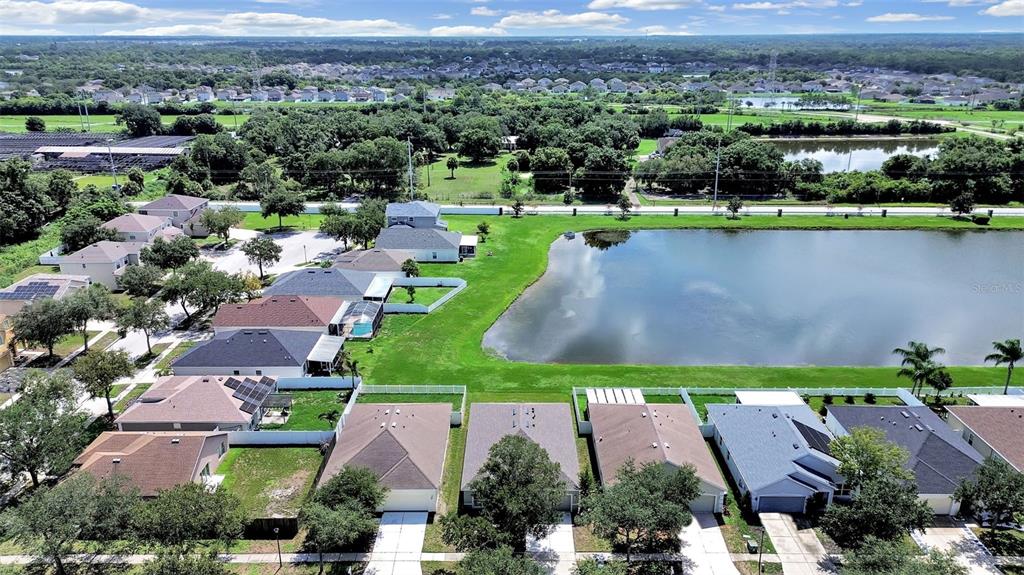An aerial view shows a suburban neighborhood with houses bordering a large retention pond — 11908 FERN BLOSSOM DRIVE, GIBSONTON, FL