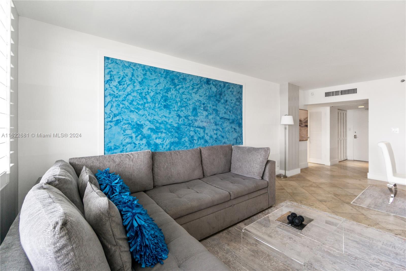 A living room features a grey sectional sofa, a blue textured wall, and tile flooring — 100 Lincoln Rd # 1422, Miami Beach FL 33139, MIAMI BEACH, FL