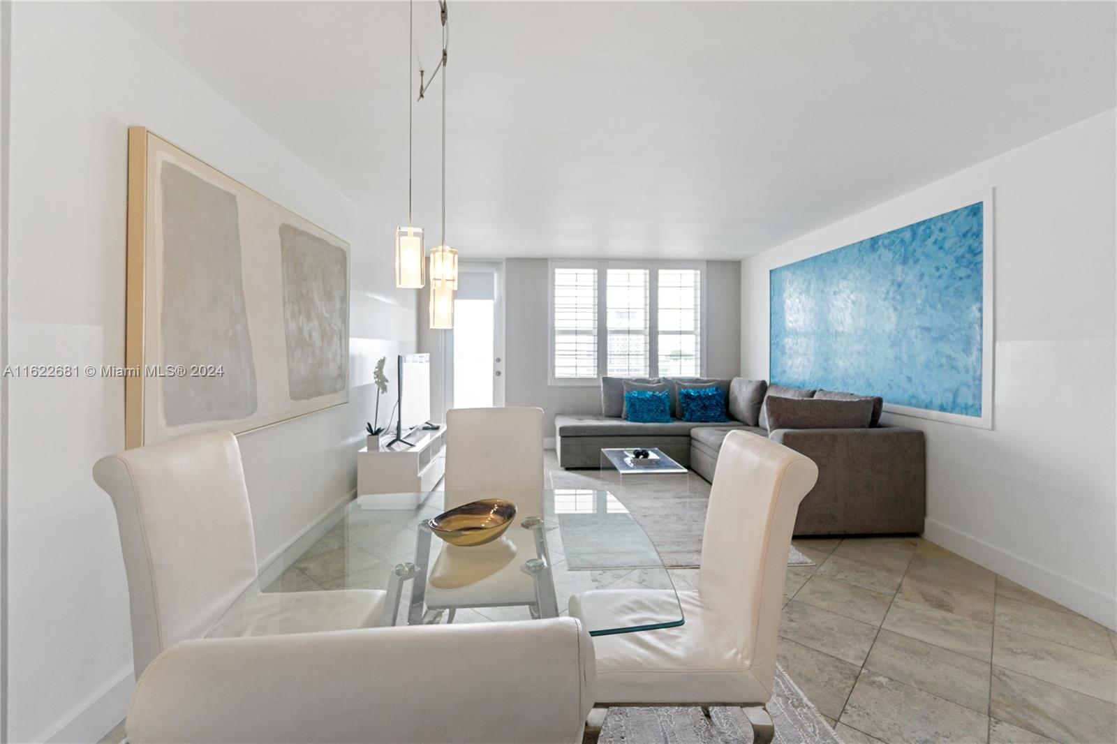 A dining area with a glass table and white chairs opens into a living room — 100 Lincoln Rd # 1422, Miami Beach FL 33139, MIAMI BEACH, FL