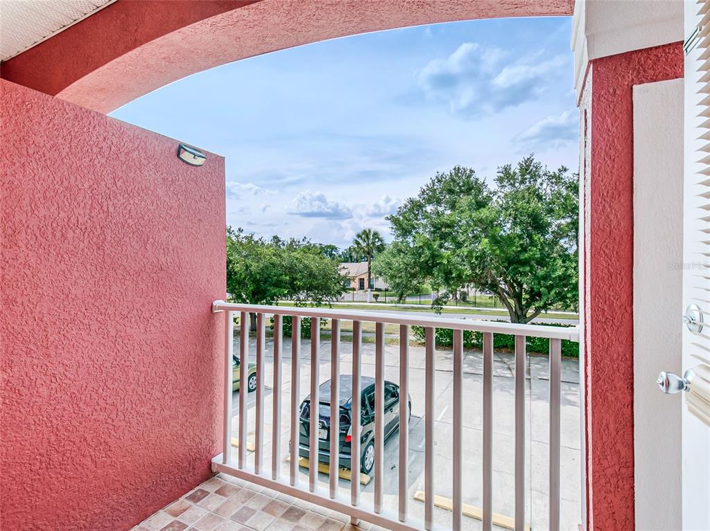 A balcony with a tiled floor, white railing, and a view of a parking lot — 261 AUTUMN LANE UNIT 3, KISSIMMEE, FL