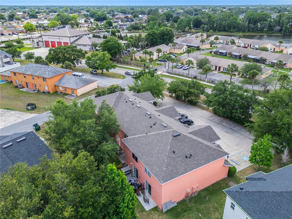 An aerial view shows a multi-story peach-colored apartment building with a gray shingled roof — 261 AUTUMN LANE UNIT 3, KISSIMMEE, FL