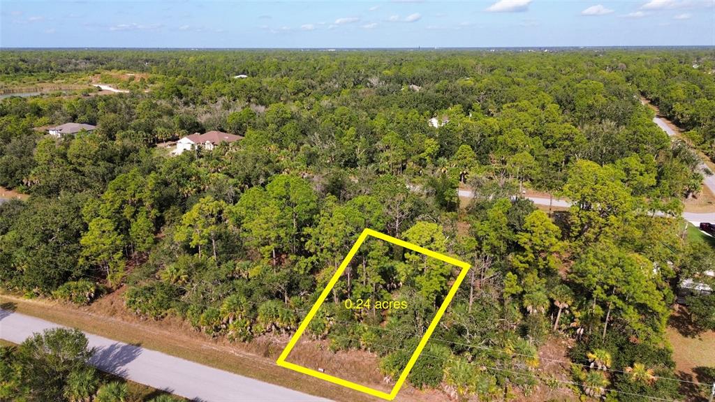 An aerial view shows a rectangular, wooded vacant lot outlined in yellow along a road — 14355 CANNELL LANE, PORT CHARLOTTE, FL