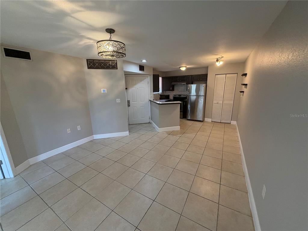 An open-concept living and kitchen area features tile flooring, neutral walls, and stainless steel appliances — 1916 LAKE ATRIUMS CIRCLE UNIT 28, ORLANDO, FL