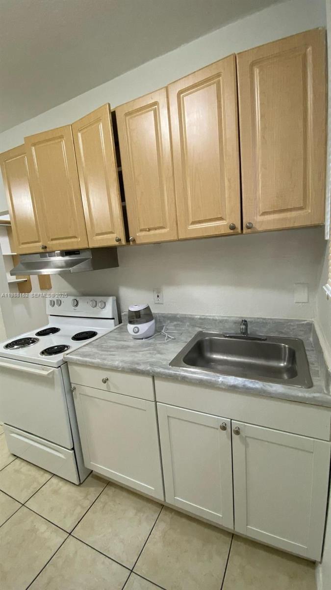 A small kitchen features light wood upper cabinets, white lower cabinets, and a white stove — 1021 NW 3rd st # 305, Miami FL 33128, MIAMI, FL