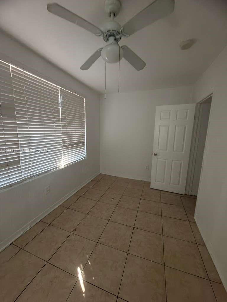 An empty room features white walls, tan tile flooring, a ceiling fan, and window blinds — 1021 NW 3rd st # 305, Miami FL 33128, MIAMI, FL