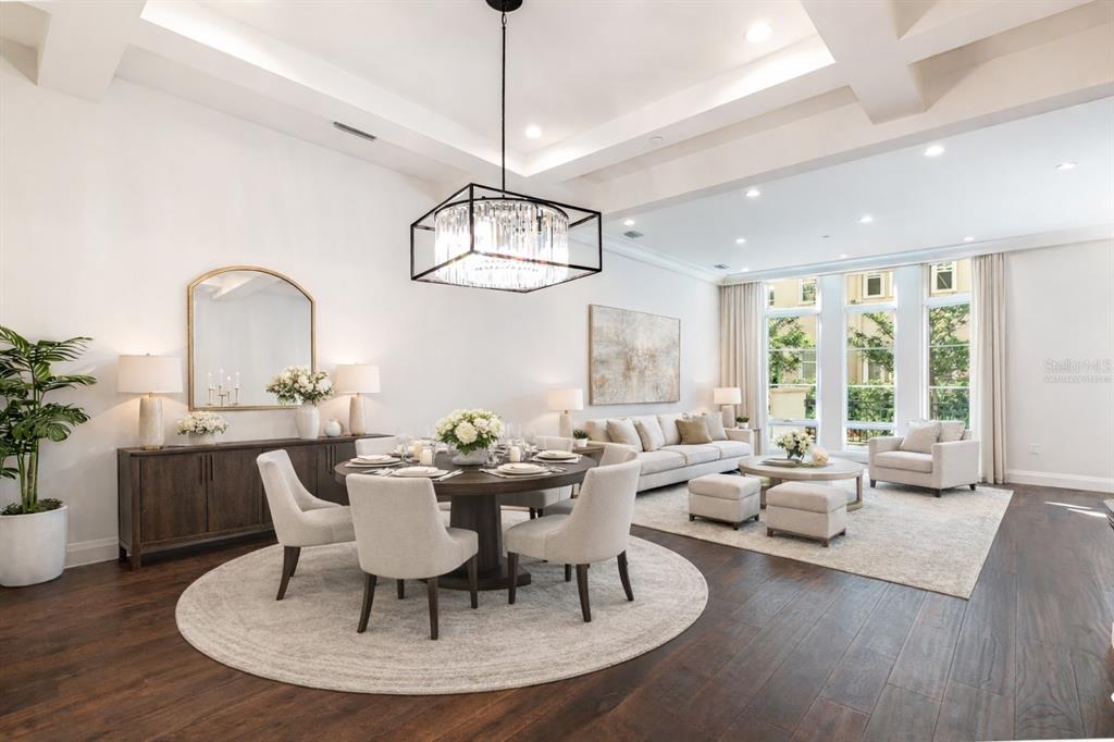 An open-concept dining and living area features dark wood floors, a coffered ceiling, and chandeliers — 125 S INTERLACHEN AVENUE UNIT 2, WINTER PARK, FL