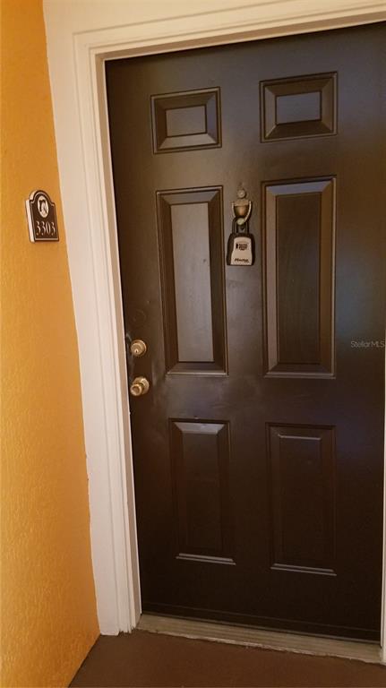 A dark brown six-panel front door with a lockbox attached to the door knocker — 5455 VINELAND ROAD UNIT 3303, ORLANDO, FL