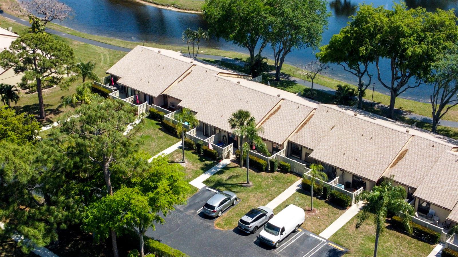 An aerial view shows a row of townhomes with a parking lot and a lake — 1017 Green Pine Boulevard # C, West Palm Beach FL 33409, WEST PALM BEACH, FL