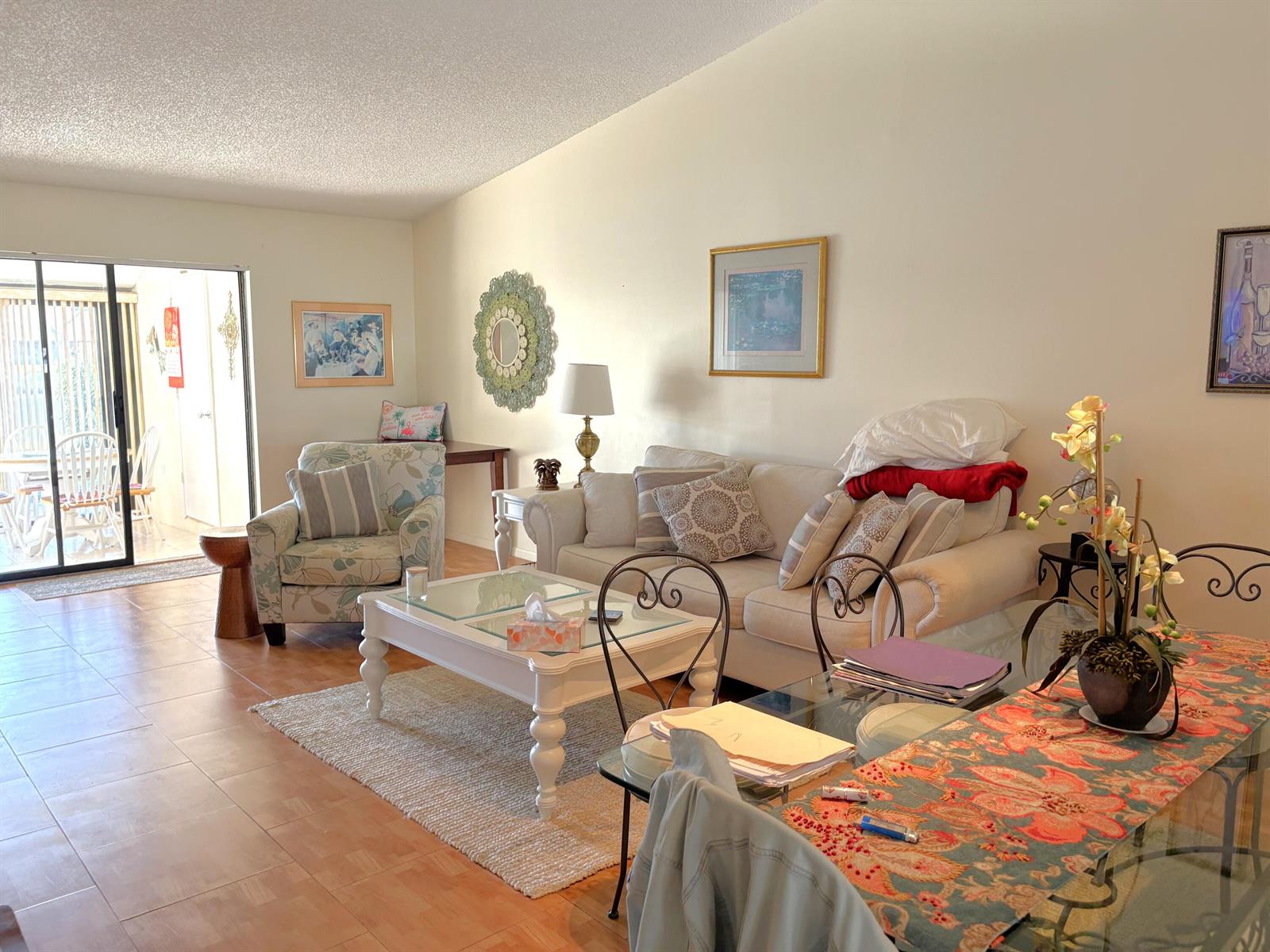 A living room with tile floors, a white sofa, a glass coffee table, and patio access — 1017 Green Pine Boulevard # C, West Palm Beach FL 33409, WEST PALM BEACH, FL