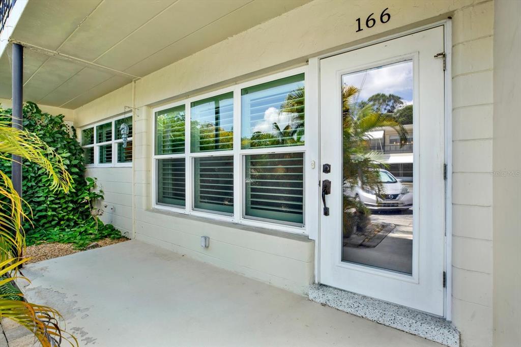 A white front door with a glass panel sits next to large windows on a porch — 4032 57TH STREET N UNIT 166, KENNETH CITY, FL