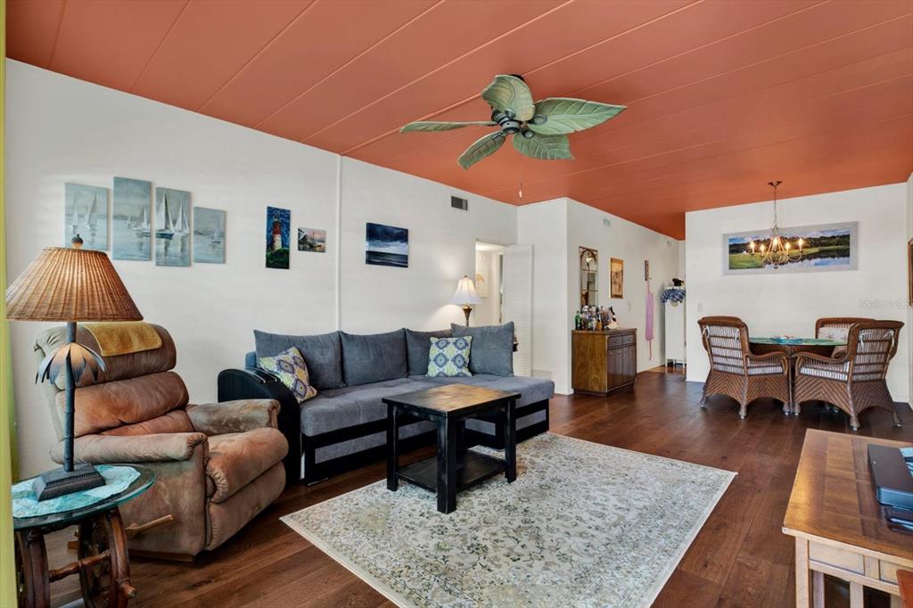 A living room features a coral-colored ceiling, dark wood floors, a sectional sofa, and furniture — 4032 57TH STREET N UNIT 166, KENNETH CITY, FL
