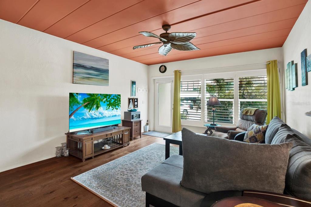 A living room features a wood-paneled ceiling, a ceiling fan, and a large television — 4032 57TH STREET N UNIT 166, KENNETH CITY, FL