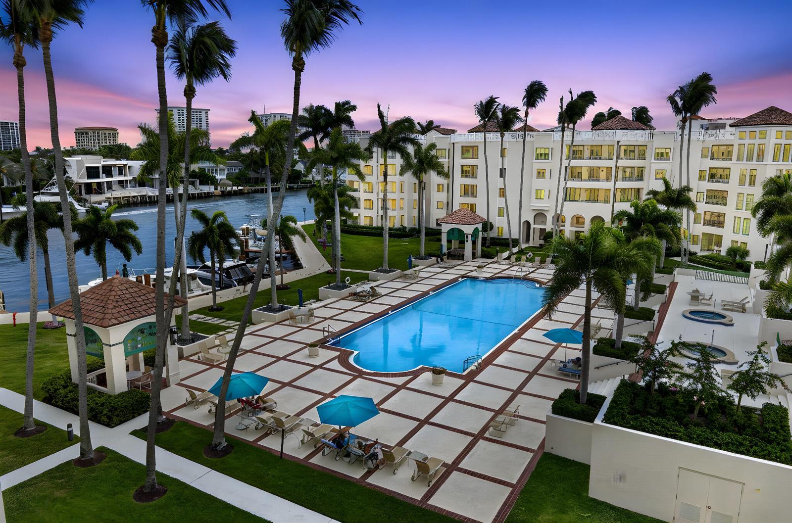An aerial view of a swimming pool area with palm trees and a waterfront building — 100 SE 5th Avenue # 7, Boca Raton FL 33432, BOCA RATON, FL