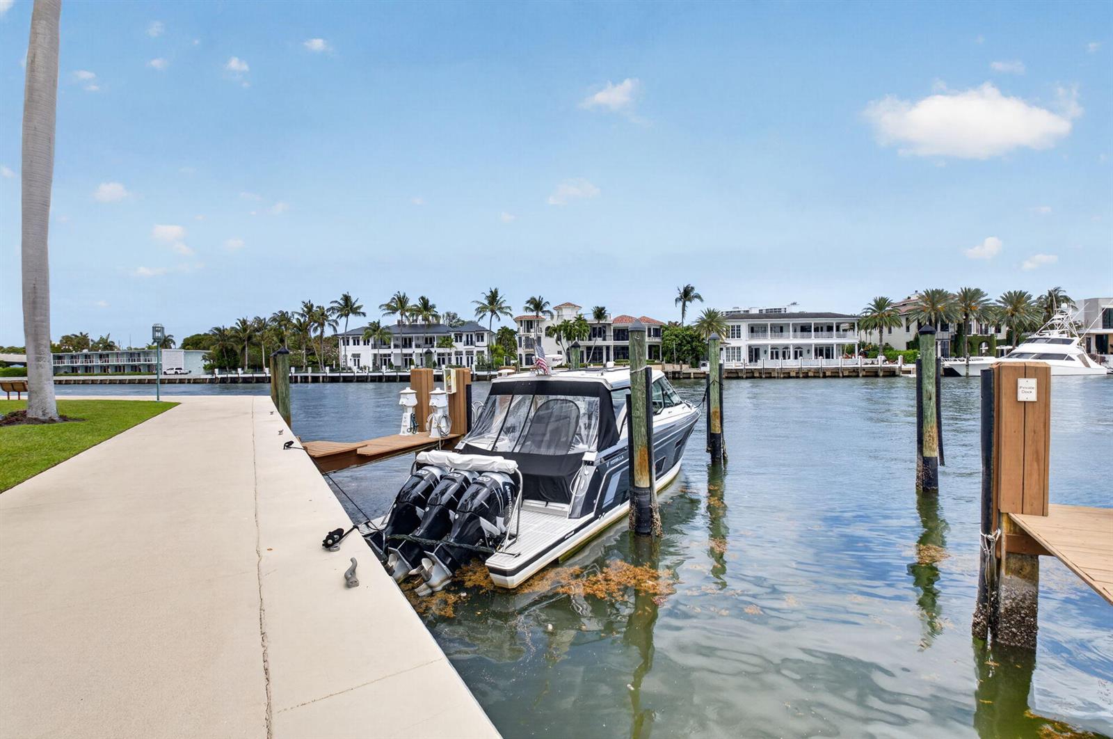 A motorboat is docked at a concrete pier along a canal lined with luxury homes — 100 SE 5th Avenue # 7, Boca Raton FL 33432, BOCA RATON, FL
