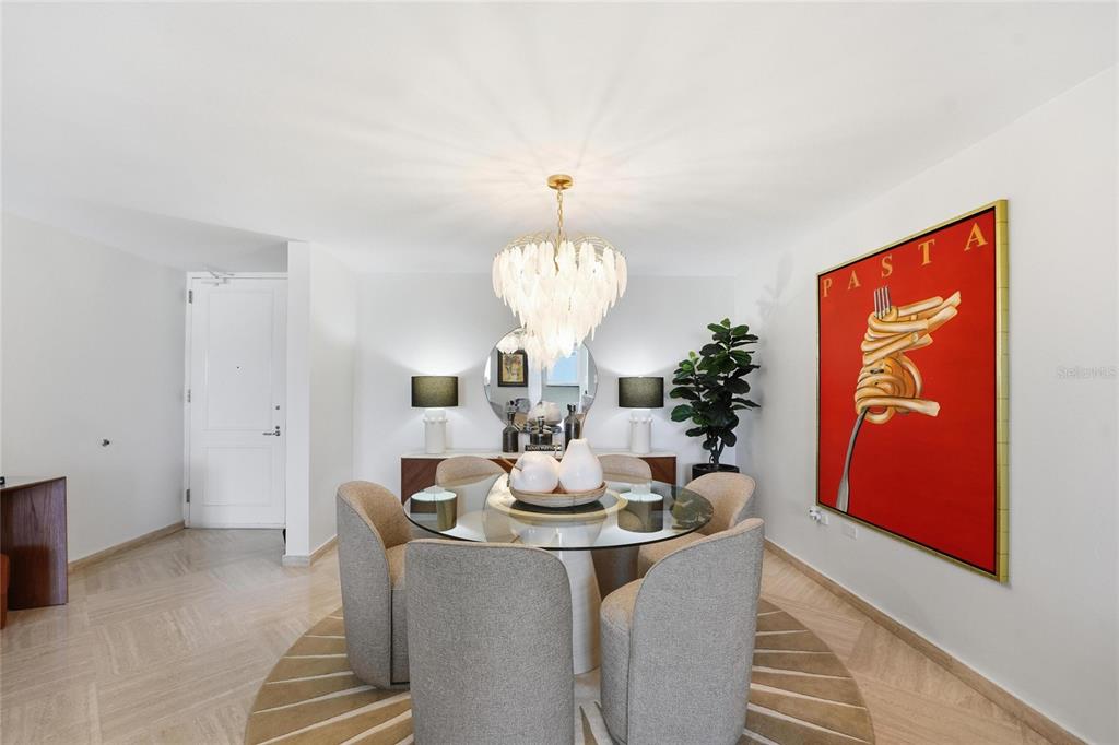 A dining room features a glass-topped table, upholstered chairs, a chandelier, and large pasta artwork — 100 JUAN A. CORRETJER UNIT PH-705, OLD SAN JUAN, PR