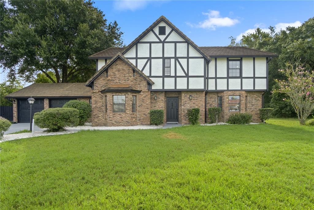 A two-story Tudor-style house with a brick facade, half-timbering, and an attached garage — 2540 ALBANY DRIVE, KISSIMMEE, FL