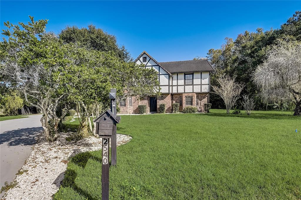 A two-story Tudor-style house with a brick and stucco exterior sits behind a front lawn — 2540 ALBANY DRIVE, KISSIMMEE, FL