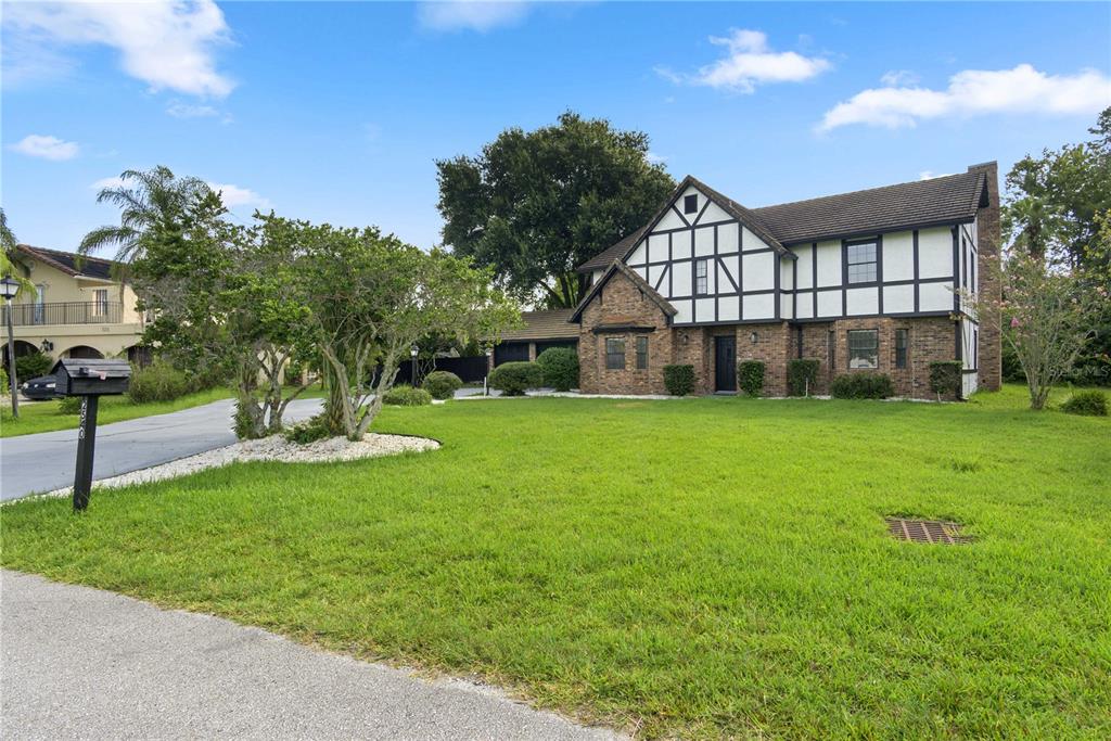 A two-story Tudor-style house with brick and timber framing sits behind a large green lawn — 2540 ALBANY DRIVE, KISSIMMEE, FL