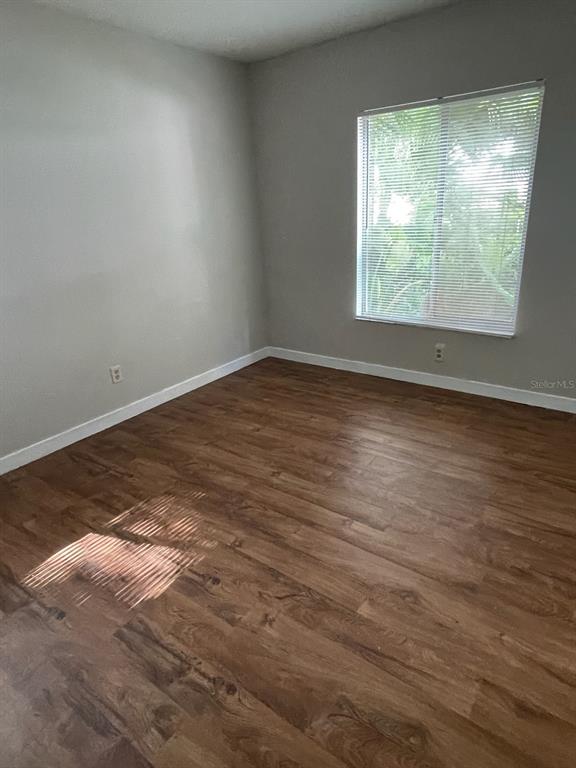 An empty room features light gray walls, wood-look flooring, and a window with blinds — 2001 SAN MARCOS DRIVE SE UNIT 11, WINTER HAVEN, FL
