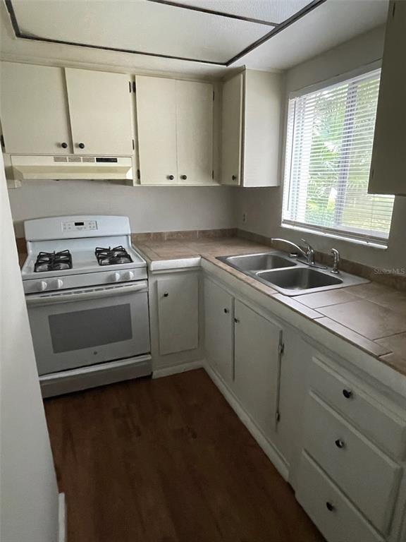 A kitchen features white cabinets, a white stove, a double sink, and tile countertops — 2001 SAN MARCOS DRIVE SE UNIT 11, WINTER HAVEN, FL