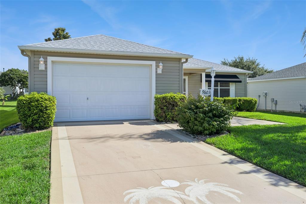 A single-story house with a garage, a concrete driveway, and green landscaping under a blue sky — 9603 SE 171ST ARGYLL STREET, THE VILLAGES, FL