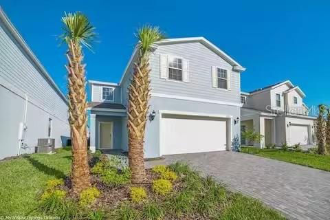 A two-story light blue house features a two-car garage and two palm trees in front — 8933 PRAGUE WAY, KISSIMMEE, FL