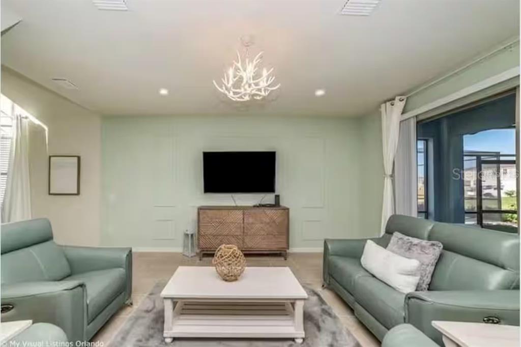 A living room features light green walls, two teal leather sofas, and a white coffee table — 8933 PRAGUE WAY, KISSIMMEE, FL