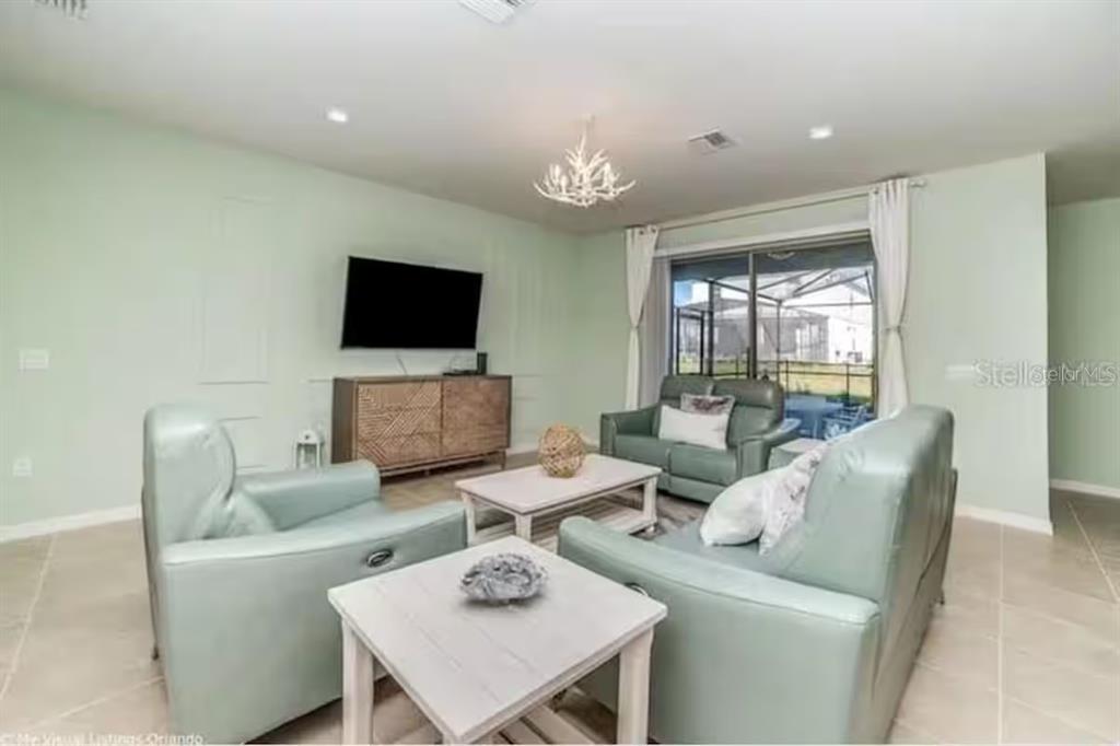 A living room features light green walls, light-colored tile flooring, and light blue leather furniture — 8933 PRAGUE WAY, KISSIMMEE, FL