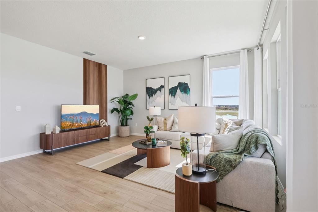 A living room features light wood flooring, a slatted wood accent wall, and a sectional sofa — 5308 CLOUDBERRY AVENUE, LAKELAND, FL