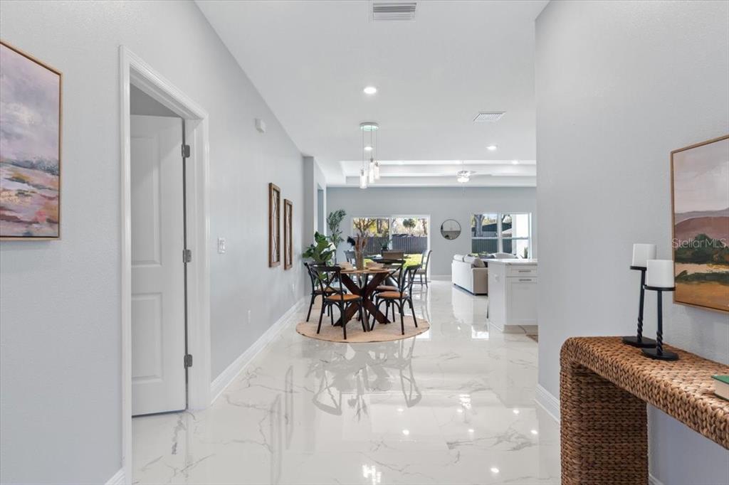 A bright hallway with white marble floors leads into an open-concept dining and living area — 6605 24TH AVENUE S, TAMPA, FL