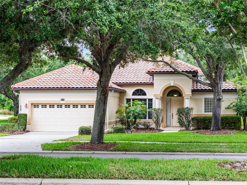 A single-story house with a tile roof, beige stucco exterior, and a two-car garage — 9958 SANTA BARBARA COURT, HOWEY IN THE HILLS, FL