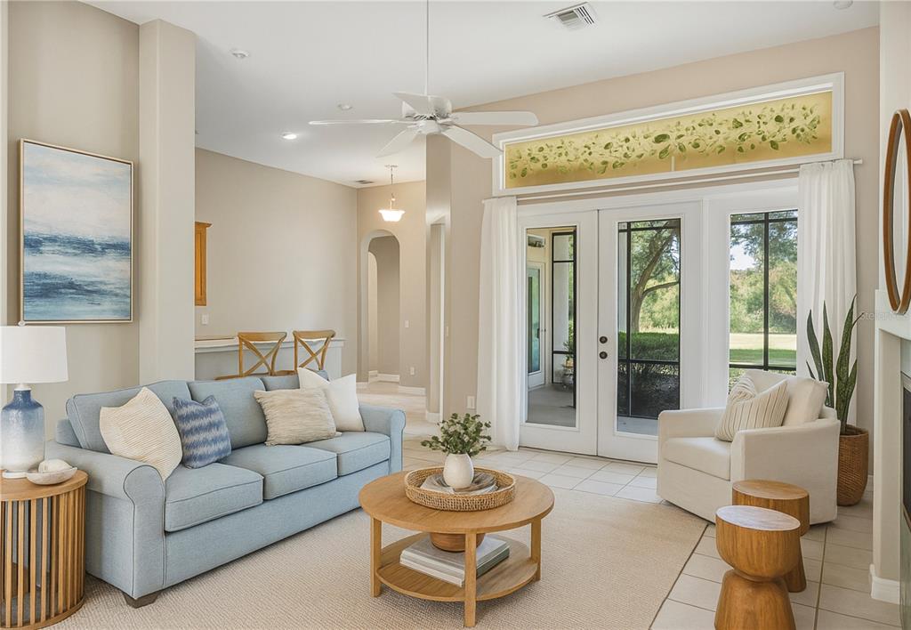 A living room with a blue sofa, white armchair, round coffee table, and glass patio doors — 9958 SANTA BARBARA COURT, HOWEY IN THE HILLS, FL