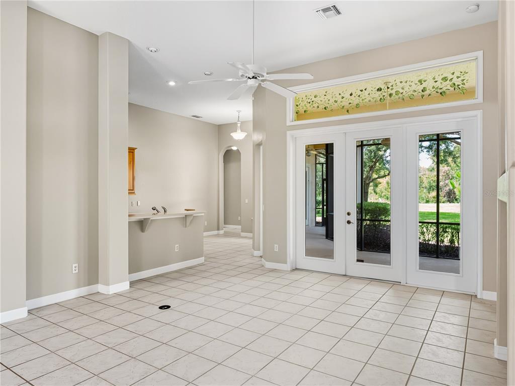 A room with light-colored tile flooring, a ceiling fan, a wet bar, and glass patio doors — 9958 SANTA BARBARA COURT, HOWEY IN THE HILLS, FL