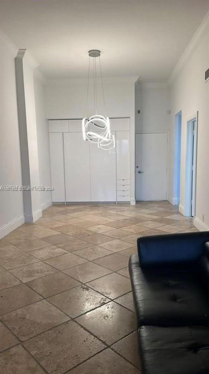 A room with light-colored tile flooring, a modern circular chandelier, and white built-in cabinetry — 6770 Indian Creek Dr, Miami Beach FL 33141, MIAMI BEACH, FL