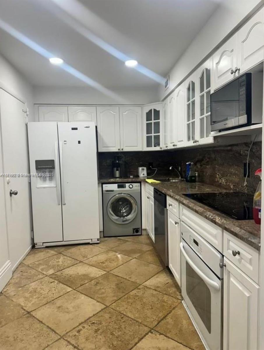 A kitchen features white cabinetry, a side-by-side refrigerator, a built-in washing machine, and stone countertops — 6770 Indian Creek Dr, Miami Beach FL 33141, MIAMI BEACH, FL