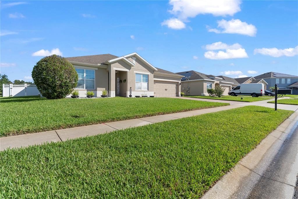A single-story suburban house with a tan exterior, a two-car garage, and a manicured lawn — 3534 CAYUGAS LOOP, ST CLOUD, FL