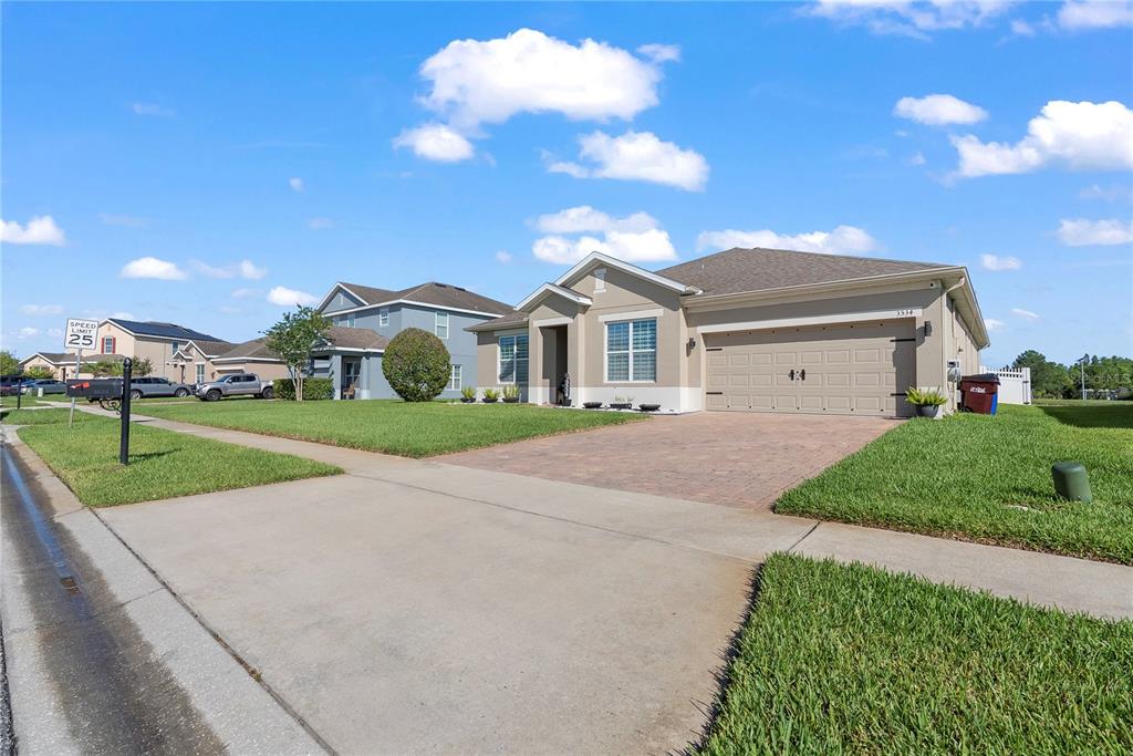 A tan single-story house with a paved driveway and a two-car garage — 3534 CAYUGAS LOOP, ST CLOUD, FL