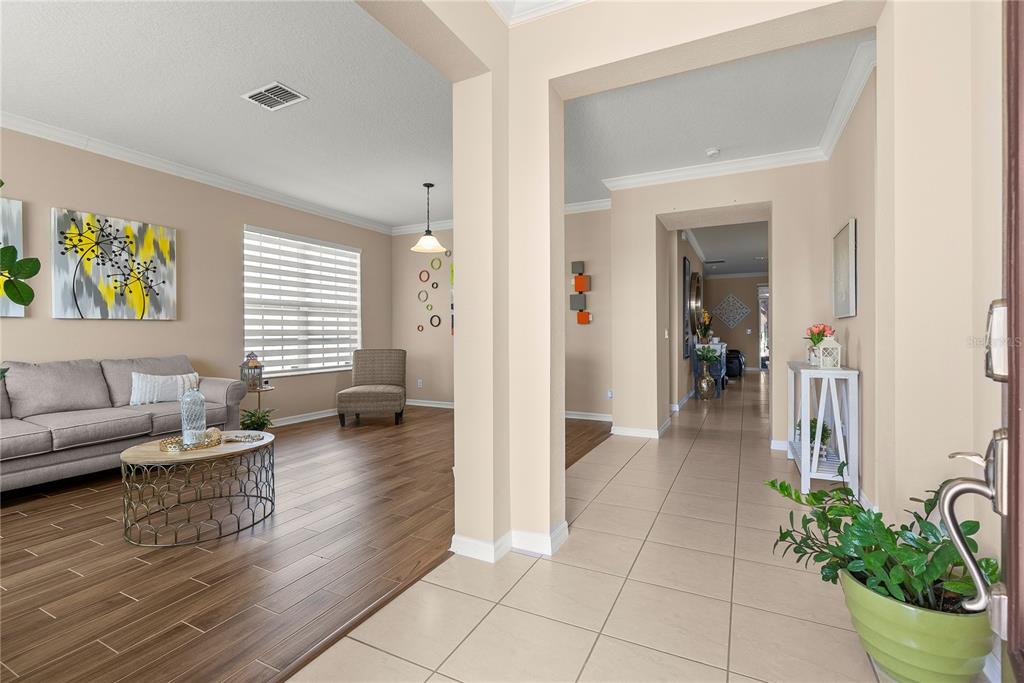 An entryway with tile flooring leads into a living room featuring wood-look floors and furniture — 3534 CAYUGAS LOOP, ST CLOUD, FL