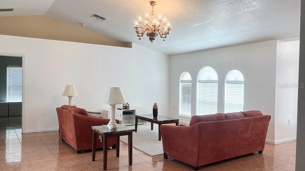 A living room features two red sofas, a chandelier, and three arched windows — 619 MAYAN PLACE, KISSIMMEE, FL