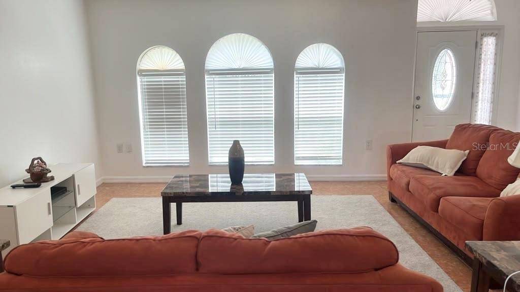 A living room features three arched windows, a coffee table, and two orange sofas — 619 MAYAN PLACE, KISSIMMEE, FL