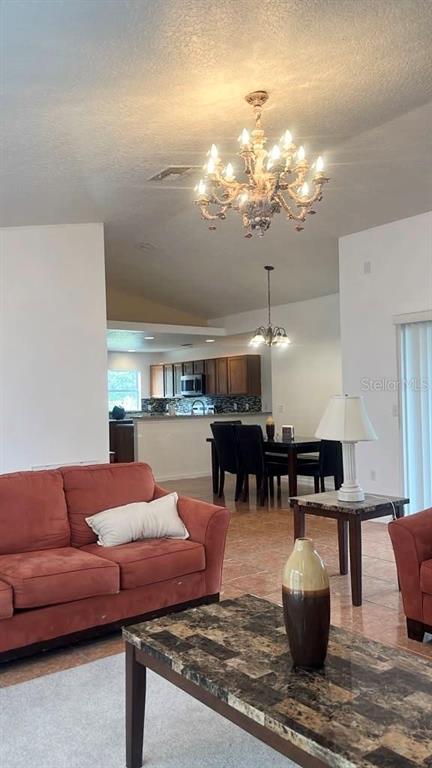 A living room with a red sofa and a dining area with a chandelier — 619 MAYAN PLACE, KISSIMMEE, FL