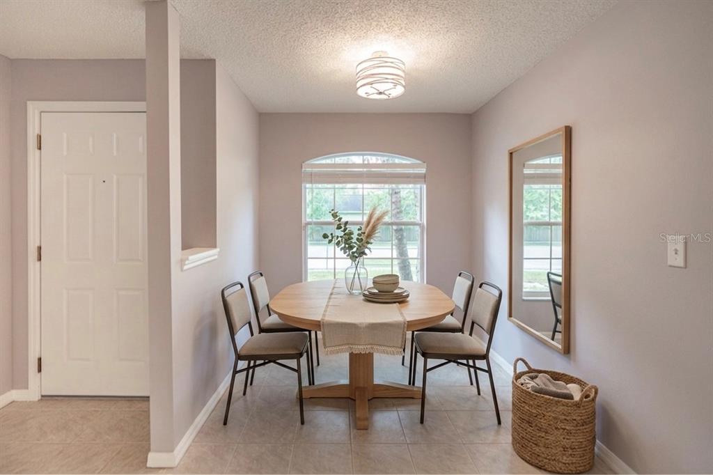 A dining room features a round wooden table, four chairs, a mirror, and tile flooring — 5437 LEHIGH AVENUE, ORLANDO, FL