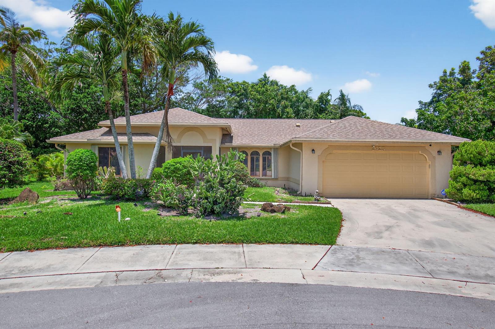 A single-story suburban house with a tan exterior, a two-car garage, and palm trees — 2925 Riviera Drive, Delray Beach FL 33445, DELRAY BEACH, FL