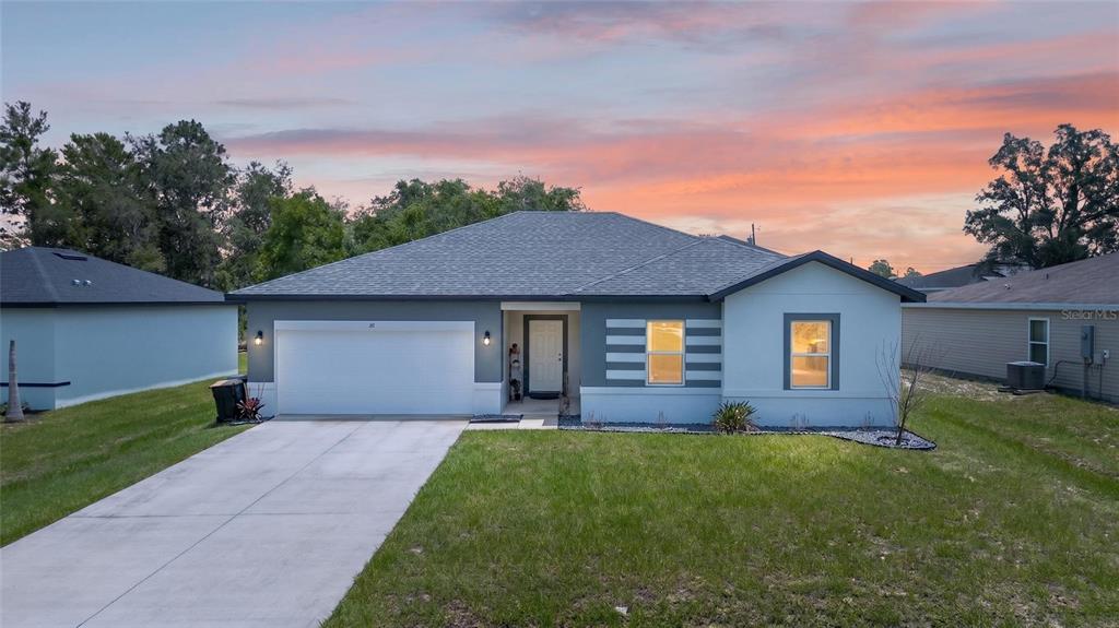 A single-story house with a white garage, gray siding, and a concrete driveway — 217 BEGONIA LANE, POINCIANA, FL